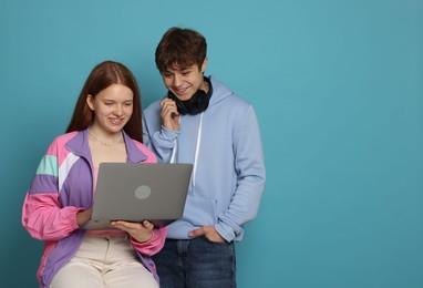 Photo of Teenage girl and boy with laptop on light blue background. Space for text