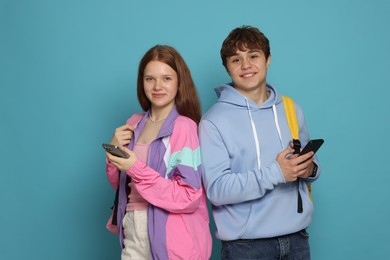 Photo of Teenage girl and boy with smartphones on light blue background