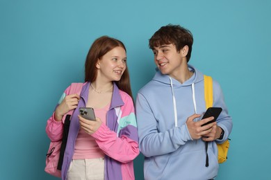 Photo of Teenage girl and boy with smartphones on light blue background