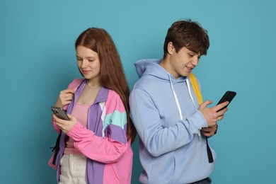 Photo of Teenage girl and boy with smartphones on light blue background