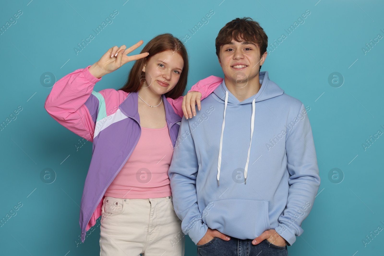 Teenage girl and boy on light blue background Photo of Teenage girl and boy on light blue background