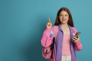 Photo of Teenage girl with smartphone on light blue background. Space for text