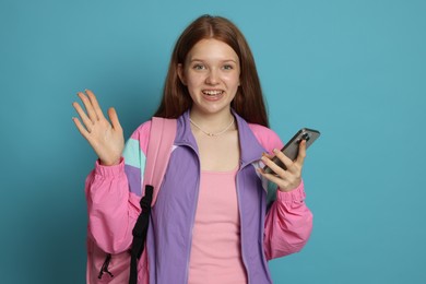 Photo of Teenage girl with smartphone on light blue background