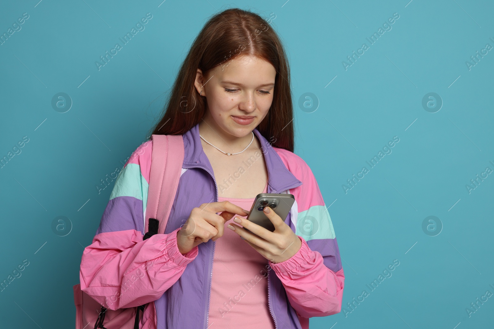 Photo of Teenage girl with smartphone on light blue background