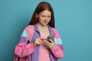 Photo of Teenage girl with smartphone on light blue background
