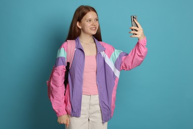 Photo of Teenage girl taking selfie on light blue background