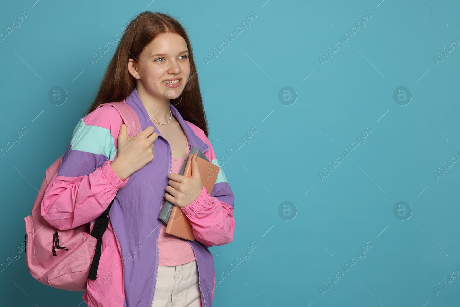 Teenage girl with books on light blue background. Space for text Photo of Teenage girl with books on light blue background. Space for text