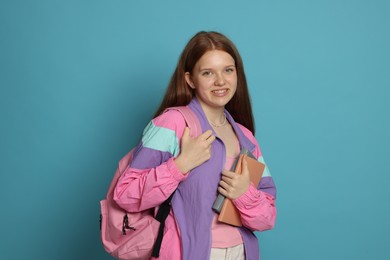 Photo of Teenage girl with books on light blue background