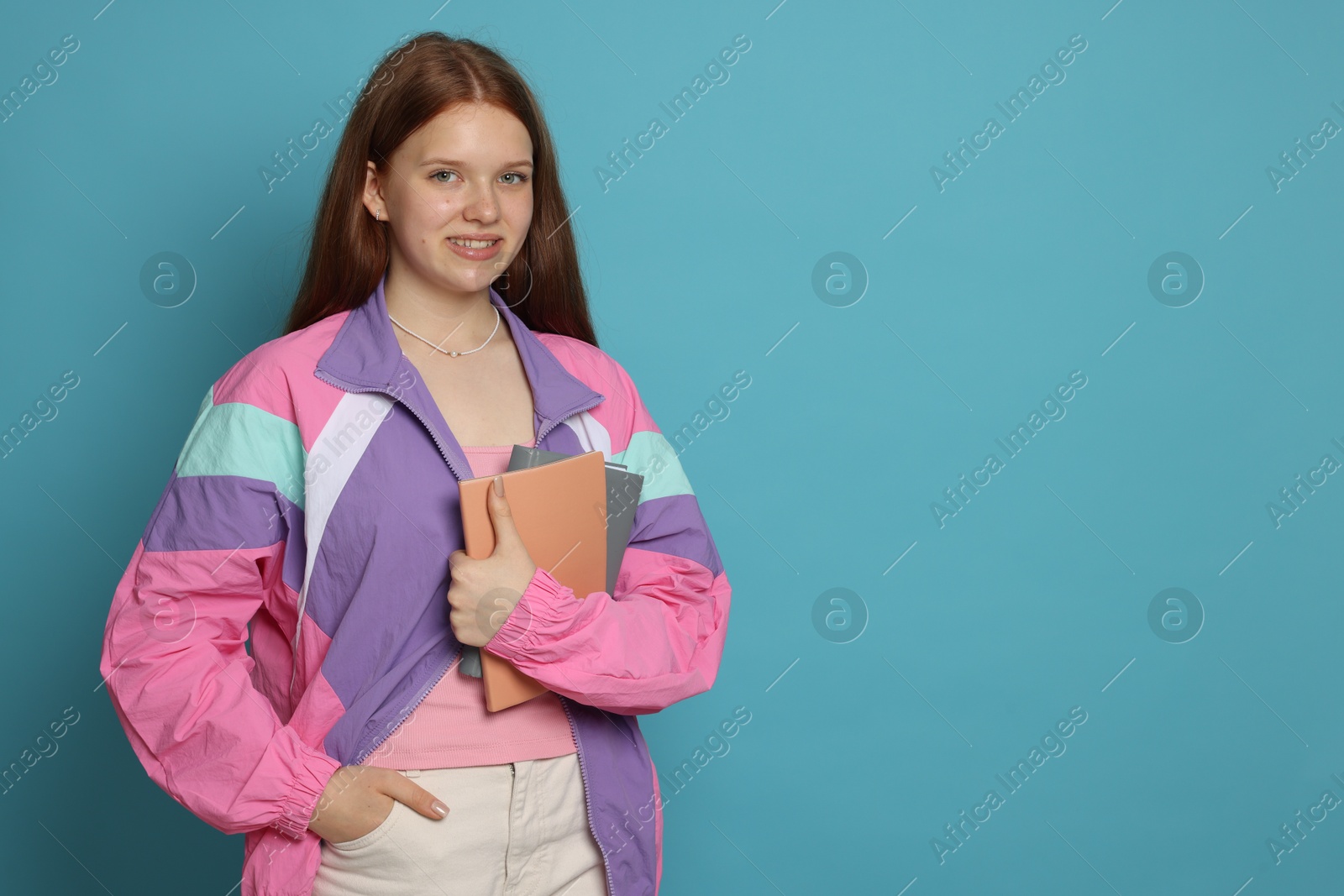 Teenage girl with books on light blue background. Space for text Photo of Teenage girl with books on light blue background. Space for text