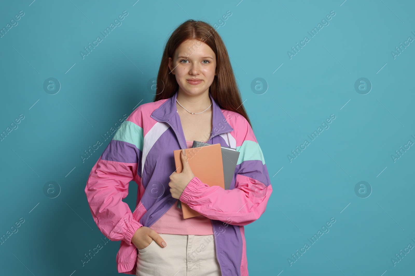 Teenage girl with books on light blue background Photo of Teenage girl with books on light blue background