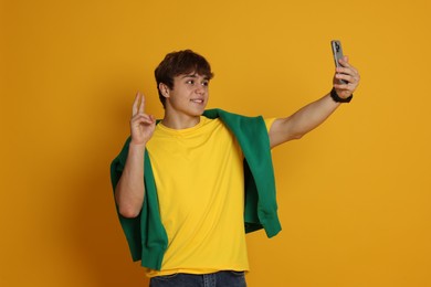 Photo of Teenage boy taking selfie on yellow background