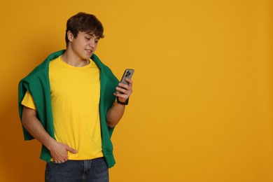 Photo of Teenage boy with smartphone on yellow background. Space for text