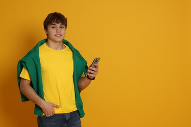 Photo of Teenage boy with smartphone on yellow background. Space for text
