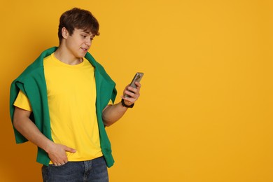 Photo of Teenage boy with smartphone on yellow background. Space for text