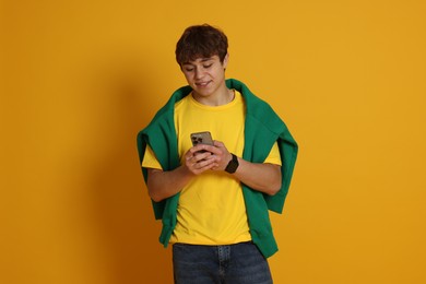 Photo of Teenage boy with smartphone on yellow background