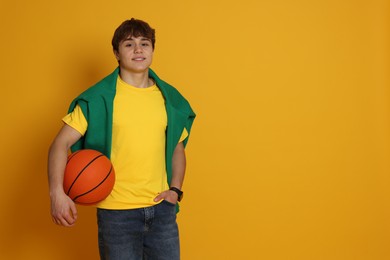 Photo of Teenage boy with basketball on yellow background. Space for text