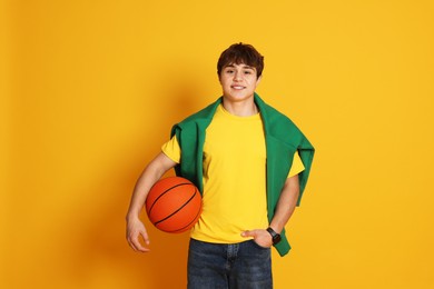 Photo of Teenage boy with basketball on yellow background