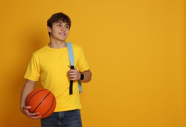 Photo of Teenage boy with basketball on yellow background. Space for text