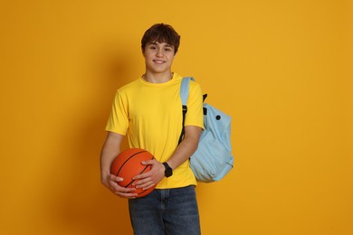 Photo of Teenage boy with basketball on yellow background