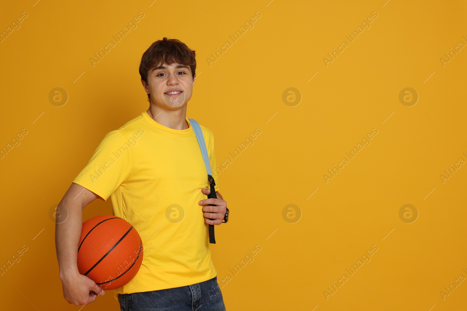 Teenage boy with basketball on yellow background. Space for text Photo of Teenage boy with basketball on yellow background. Space for text