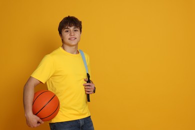 Photo of Teenage boy with basketball on yellow background. Space for text