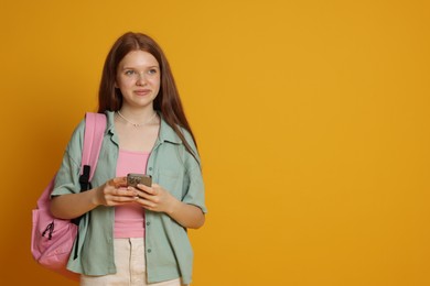 Photo of Teenage girl with smartphone on yellow background. Space for text