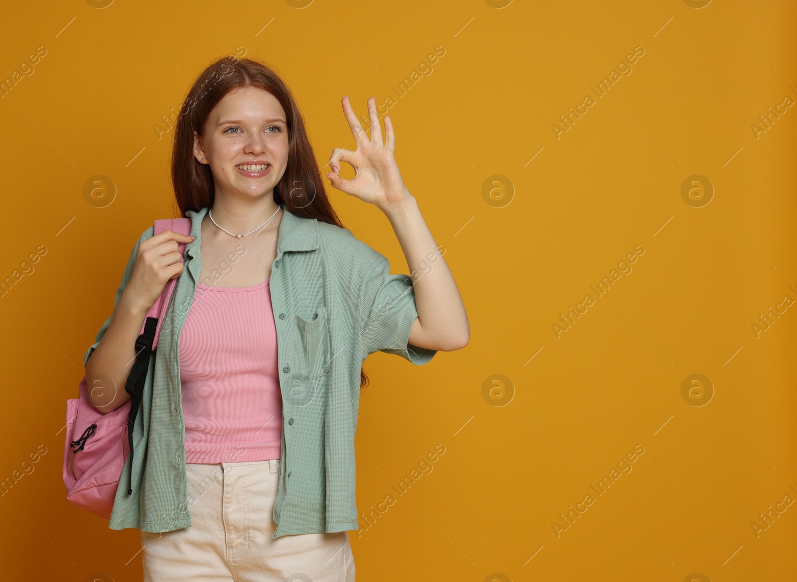 Photo of Teenage girl showing okay gesture on yellow background. Space for text