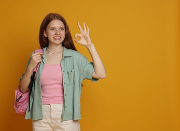 Photo of Teenage girl showing okay gesture on yellow background. Space for text