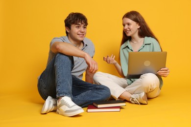 Photo of Teenage girl and boy with laptop on yellow background