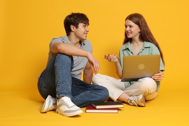 Photo of Teenage girl and boy with laptop on yellow background