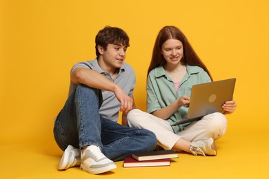 Photo of Teenage girl and boy with laptop on yellow background