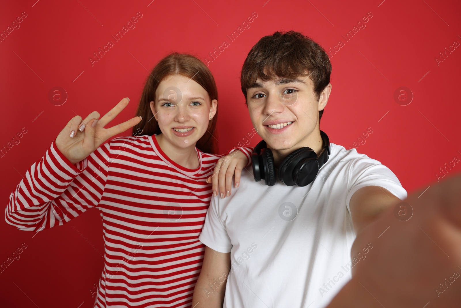 Teenage girl and boy taking selfie on red background Photo of Teenage girl and boy taking selfie on red background