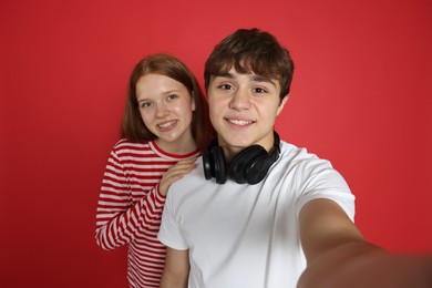 Photo of Teenage girl and boy taking selfie on red background