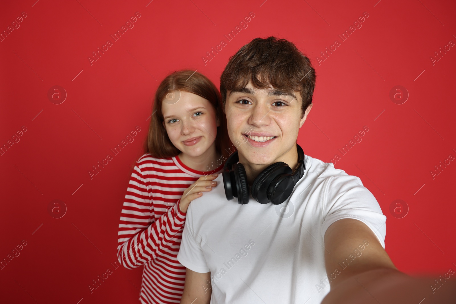 Teenage girl and boy taking selfie on red background Photo of Teenage girl and boy taking selfie on red background
