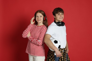 Photo of Teenagers with headphones and soccer ball on red background