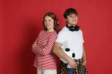 Photo of Teenagers with headphones and soccer ball on red background