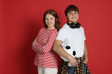 Photo of Teenagers with headphones and soccer ball on red background