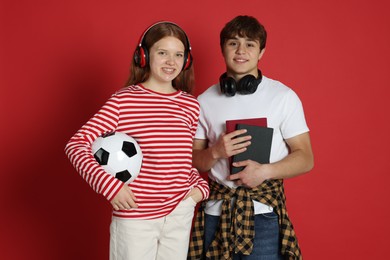 Photo of Teenagers with headphones, books and soccer ball on red background