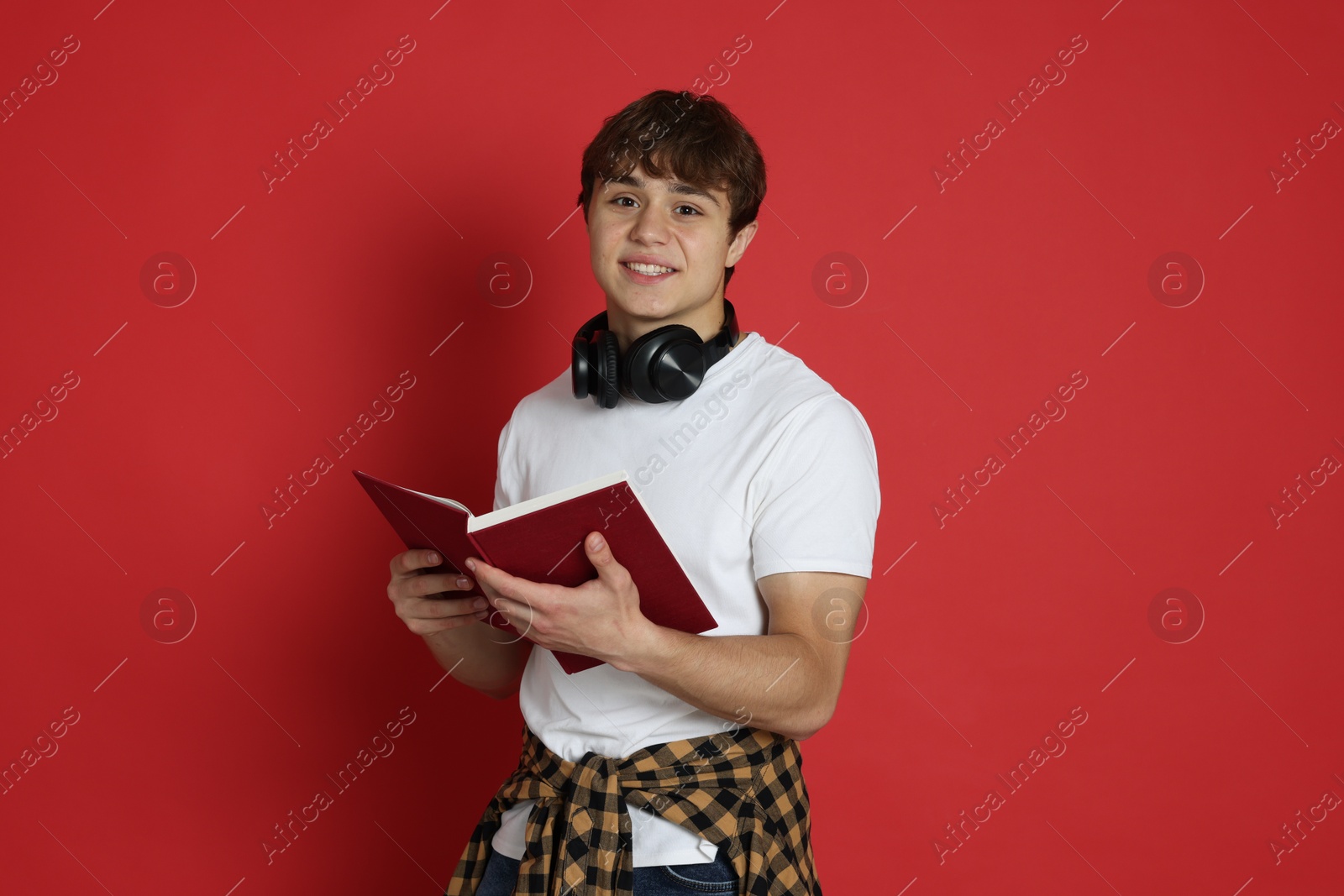 Teenage boy with book on red background Photo of Teenage boy with book on red background