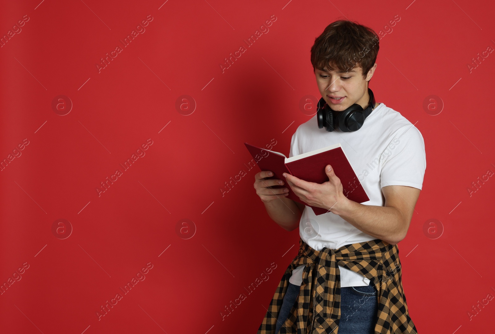 Teenage boy with book on red background. Space for text Photo of Teenage boy with book on red background. Space for text