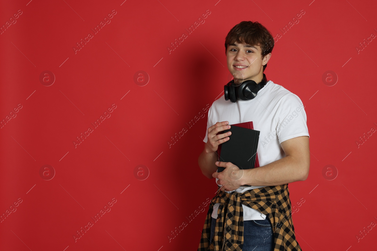 Teenage boy with books on red background. Space for text Photo of Teenage boy with books on red background. Space for text