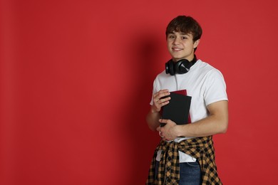 Photo of Teenage boy with books on red background. Space for text