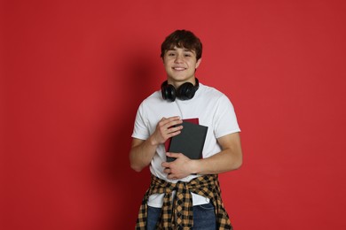 Photo of Teenage boy with books on red background