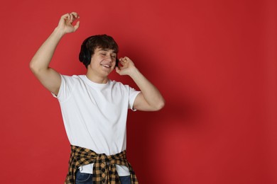 Photo of Teenage boy listening to music on red background. Space for text