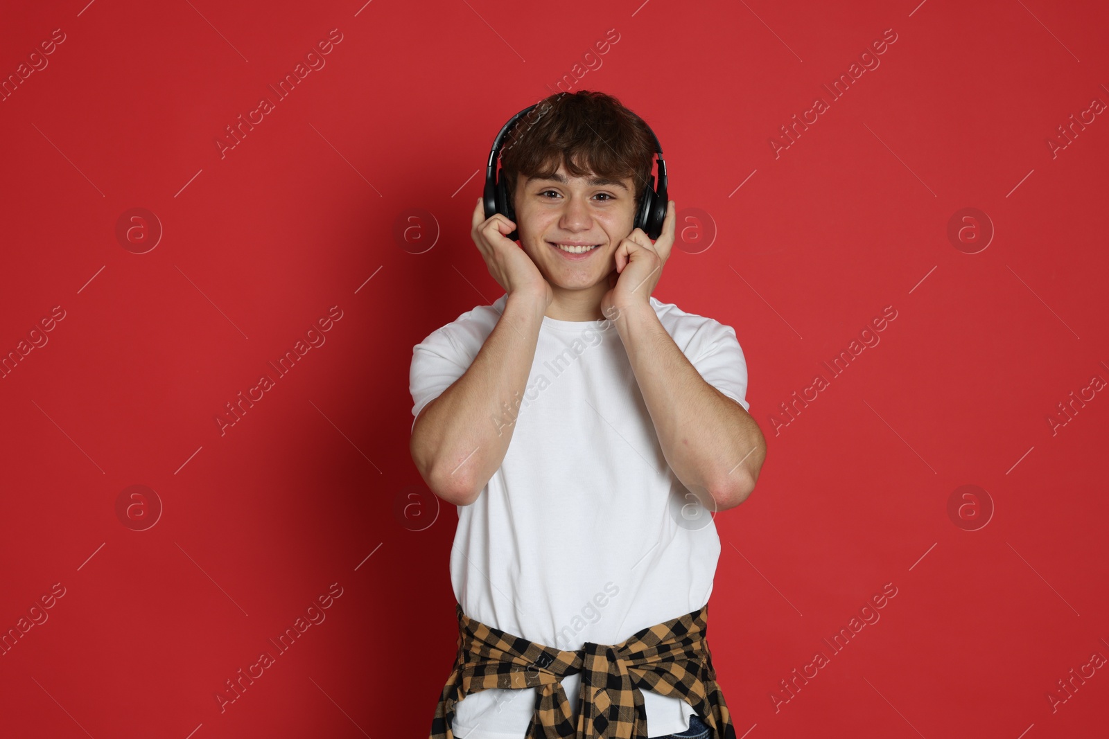 Teenage boy listening to music on red background Photo of Teenage boy listening to music on red background