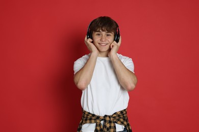 Photo of Teenage boy listening to music on red background