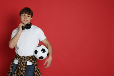 Photo of Teenage boy with soccer ball on red background. Space for text