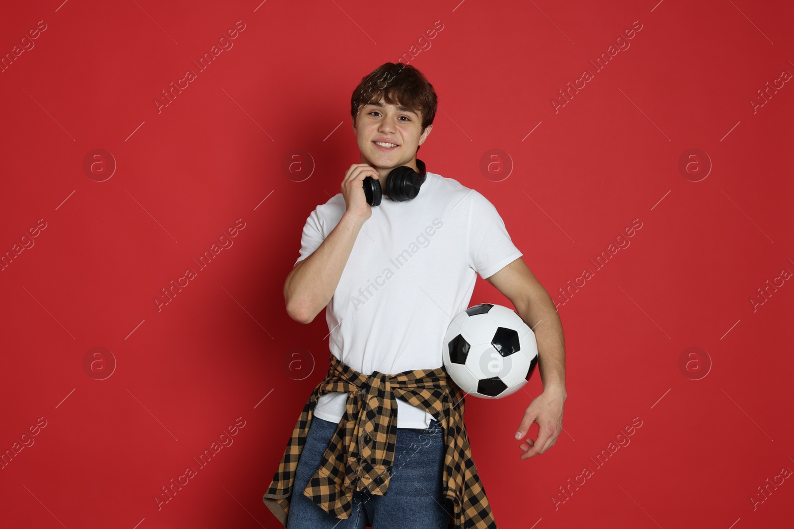 Teenage boy with soccer ball on red background Photo of Teenage boy with soccer ball on red background