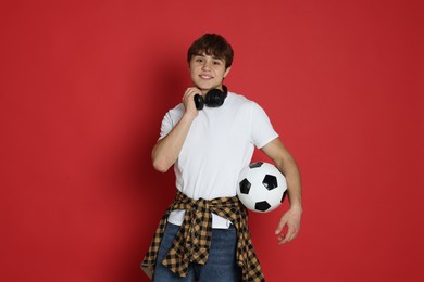 Photo of Teenage boy with soccer ball on red background
