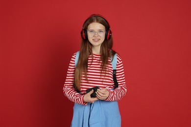 Photo of Teenage girl with smartphone listening to music on red background
